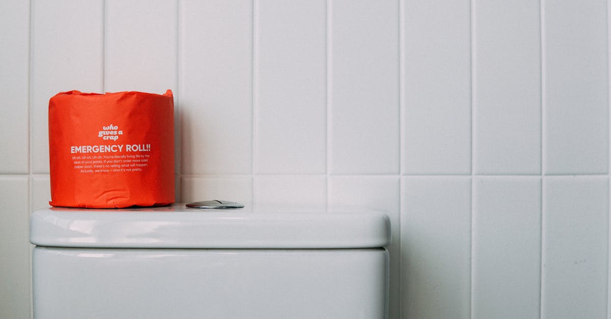 minimalist bathroom scene featuring a red emergency toilet paper roll on a white toilet tank